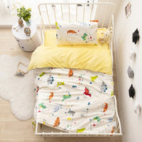 Ensemble Housse de Couette Bebe avec Imprimé de Dinosaure sur un lit avec une petite table et un tapis à gauche