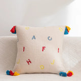 Housse Coussin Canapé Blanche avec Lettres et Pompons sur un canapé