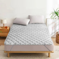 Surmatelas Design et Respirant installé sur un lit avec deux coussins et une table de nuit avec une lampe dessus à gauche