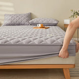 Surmatelas avec Motifs en Forme de Losange en train d'être installé par une personne sur un lit avec deux coussins